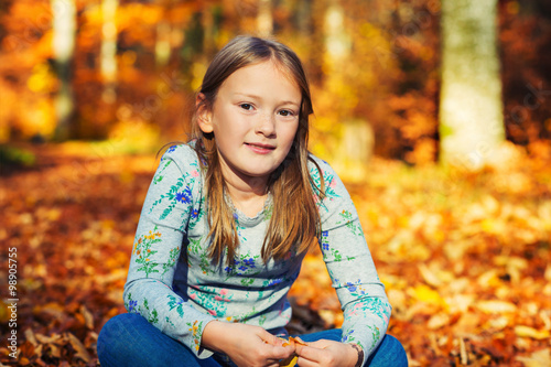 Outdoor portrait of a cute little girl in autumn forest, toned image
