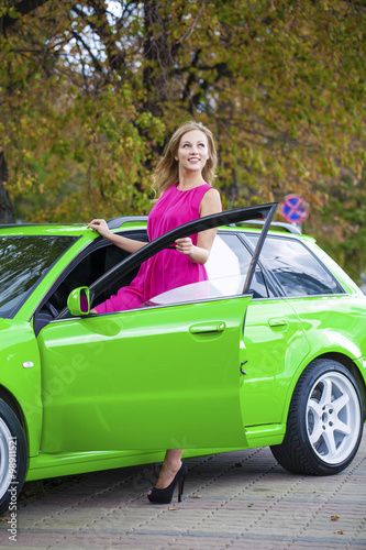 Portrait of a beautiful blonde woman and green sports car