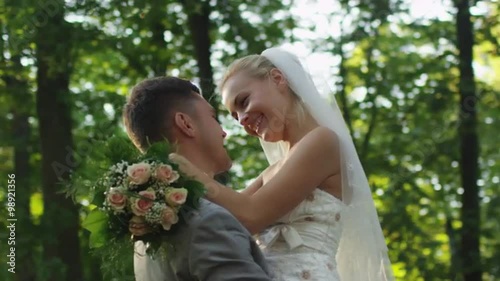 Just married couple hug each other in a sunny park