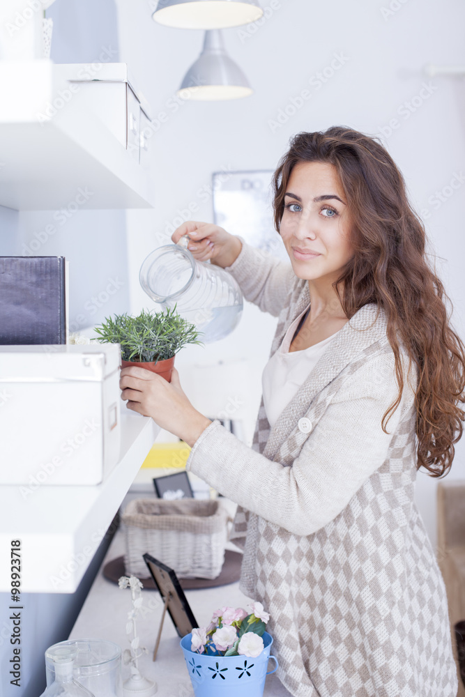 Beautiful woman arranging flowers and decorating her living room Shallow depth of field. Beautiful woman arranging flowers and decorating her living room Shallow depth of field.
