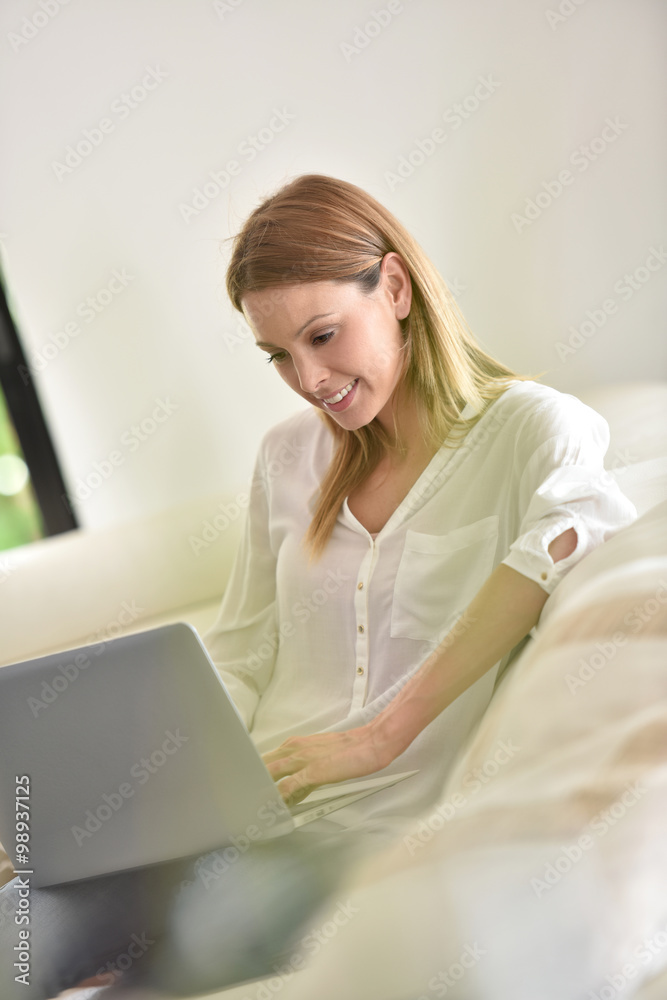 Woman relaxing in sofa and websurfing with laptop Woman relaxing in sofa and websurfing with laptop