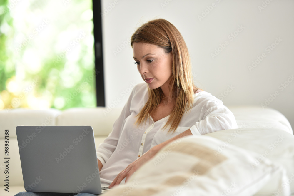 Woman relaxing in sofa and websurfing with laptop Woman relaxing in sofa and websurfing with laptop