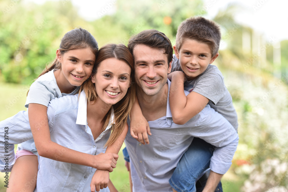 Parents giving piggyback ride to kids outside Parents giving piggyback ride to kids outside