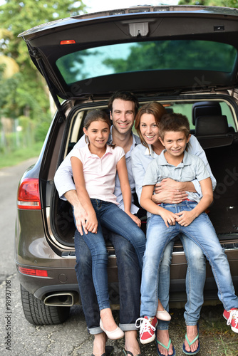 Family sitting in car trunk, ready for vacation