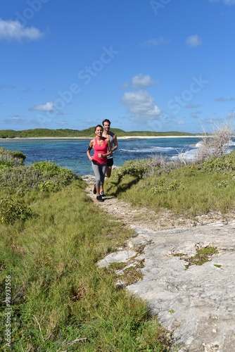 Couple of joggers running by the sea