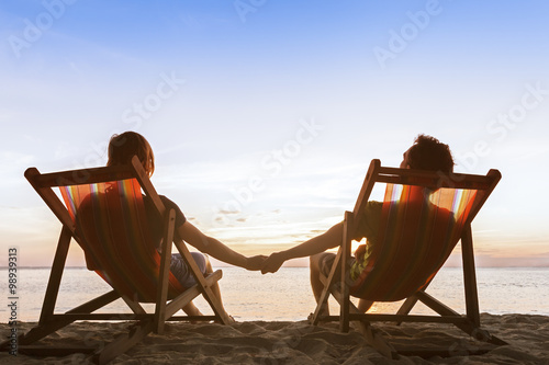 Canvas Print Couple in deckchairs on the beach enjoying beautiful sunset