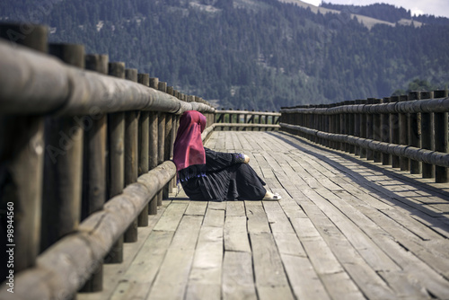 Female sitting on wooden path in nature photo