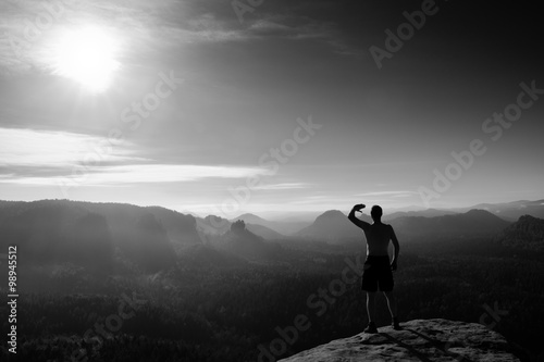 Climber in black pants. Gesture of triumph. Body naked man on the peak of sandstone rock in national park Saxony Switzerland