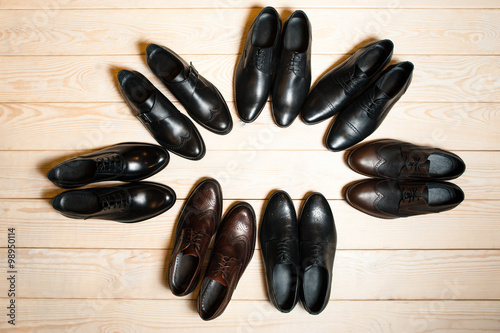 many leather men's shoes on wooden background