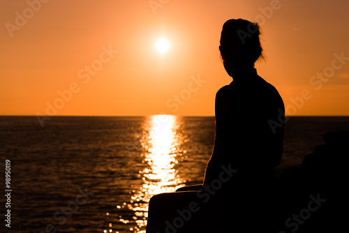 Eine Frau entspannt beim Sonnenuntergang am Meer