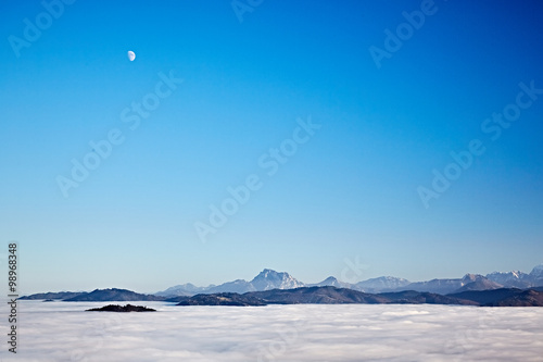 Clear blue sky over the mountains and clouds in the valley