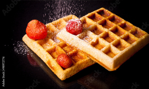 Traditional belgium soft waffles with strawberries and powdered