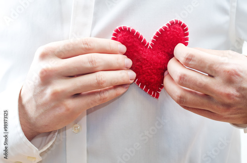 Men's hands hold a toy heart