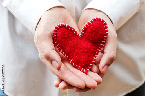 Men's hands hold a toy heart