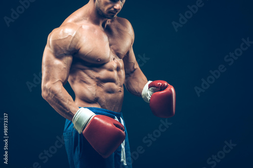 Muscular boxer in studio shooting, on black background. © satyrenko
