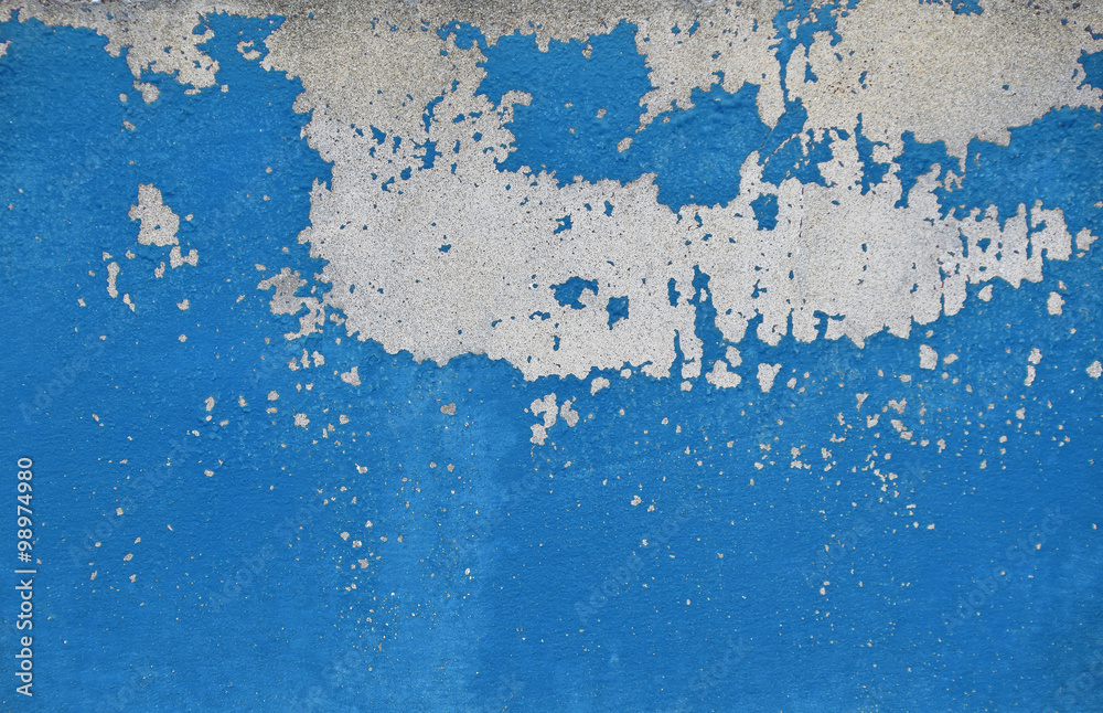 Fototapeta premium Flakes of old blue paint on grey concrete wall