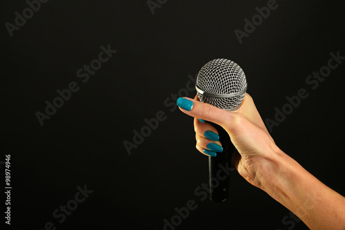 Canvastavla Woman hand with microphone isolated on black