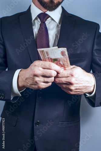 Bearded man in suit holds Russian rubles