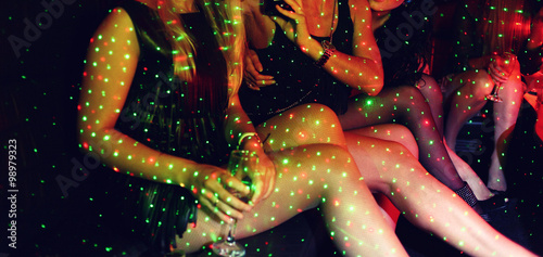 Legs of many girls in night club with spots of party lights