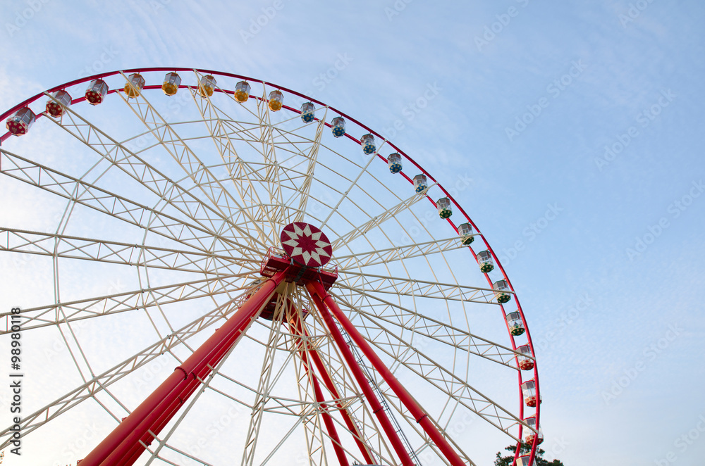 Ferris wheel with cabins on the background of cirrus clouds and blue sky. A horizontal view. Gorky Park. Kharkov, Ukraine. Ferris wheel with cabins on the background of cirrus clouds and blue sky. A horizontal view. Gorky Park. Kharkov, Ukraine.