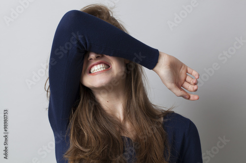 Foto despair and anger concept - shocked young woman hiding her face with her arm,gri