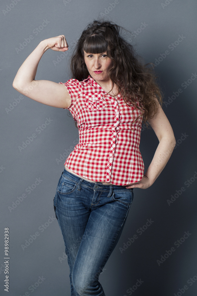 muscle concept - proud young woman with tomboy retro look raising her arm to enjoy female power, symbol of freedom,studio shot muscle concept - proud young woman with tomboy retro look raising her arm to enjoy female power, symbol of freedom,studio shot