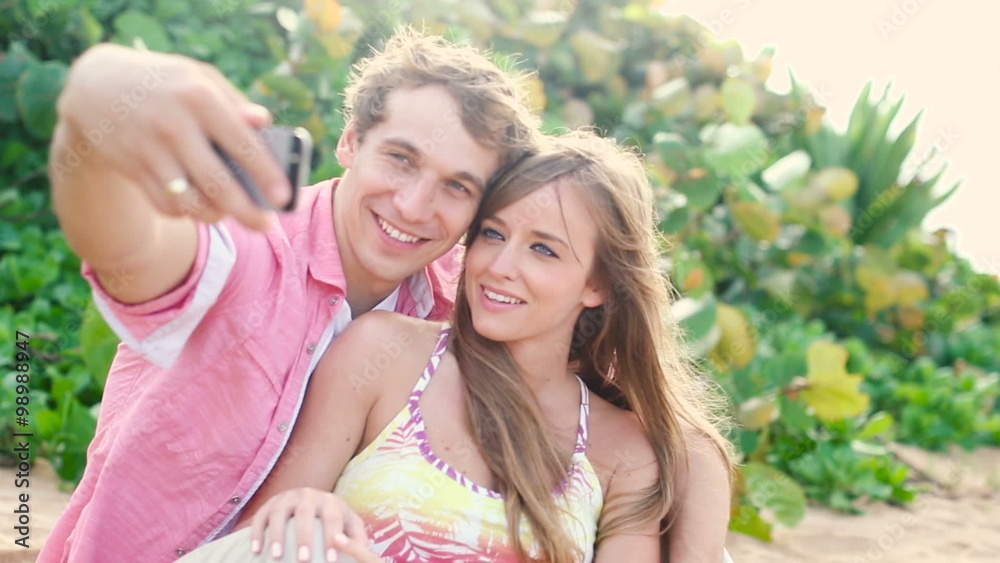 Smiling young couple in love taking self portrait with camera phone on beach Smiling young couple in love taking self portrait with camera phone on beach