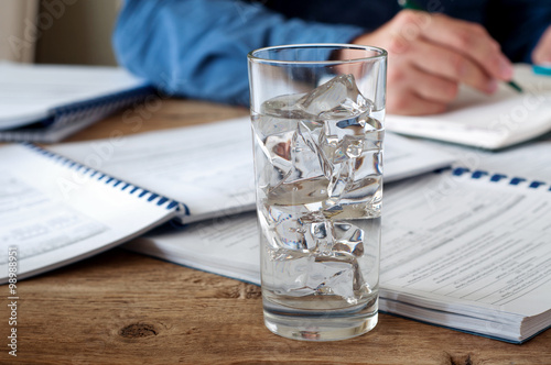 Glass of water with ice on a wooden office teble
