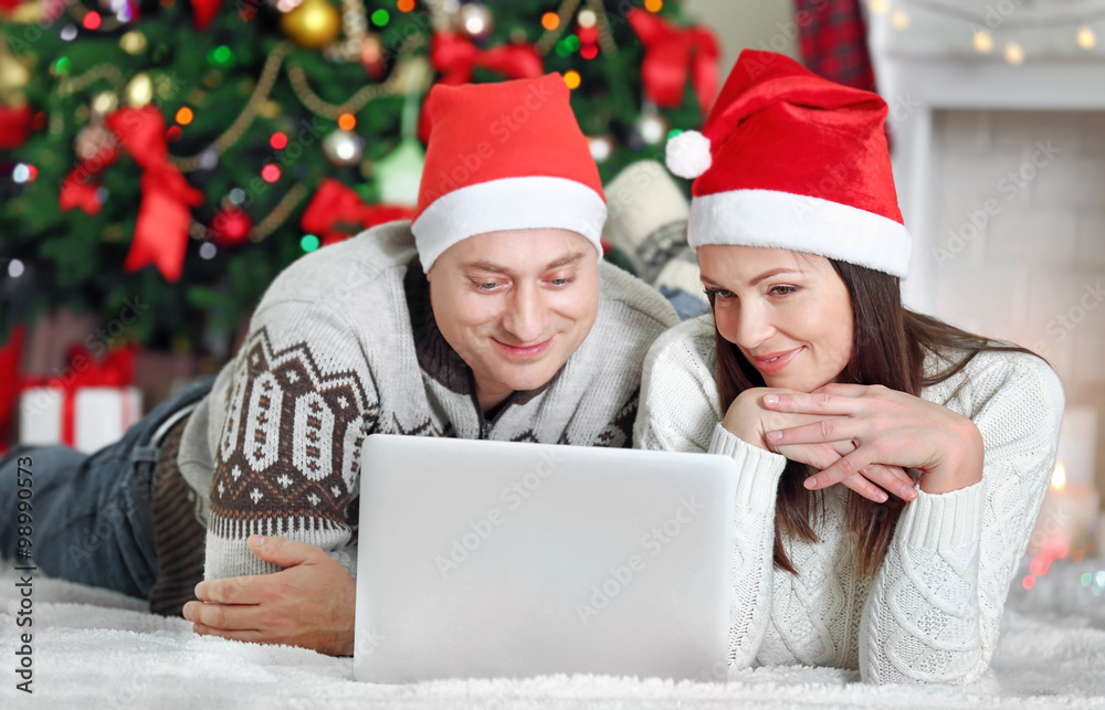 Happy Family with laptop on Christmas tree background Happy Family with laptop on Christmas tree background