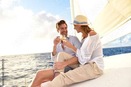 Romantic couple cheering on sailboat at sunset