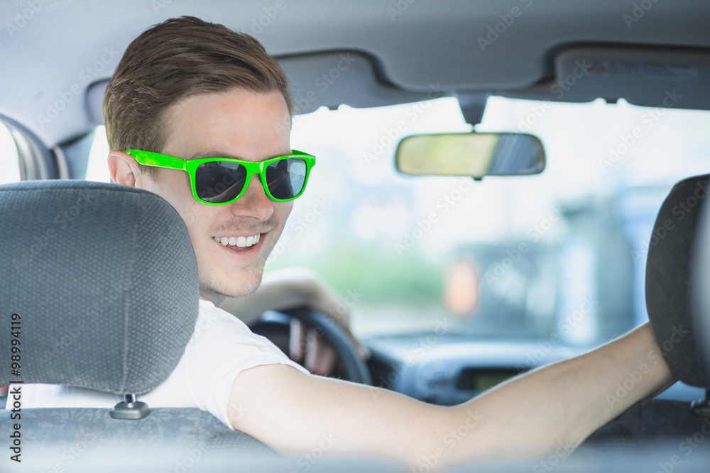 Naklejka premium Junger Mann mit Sonnenbrille sitzt im Auto
