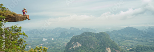 Travel concept. Young man tourist - photographer taking photo at mountain peak. Panoramic banner. Thailand. Krabi . 