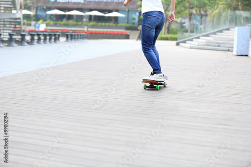 woman skateboarder legs riding skateboard on wooden boardwalk