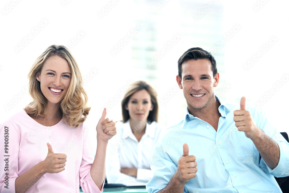 Young couple with thumbs up at the bank. Financial adviser out of focus in the background. 