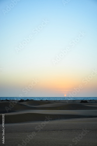 Sunrise over sandy dunes in desert / Sandy and wavy dunes with stylish forms in a wide desert under blue sky