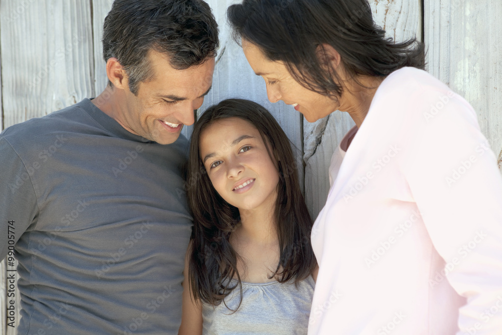 Family with one child - Two parents with their daughter. They look at her. She looks at the camera. Family with one child - Two parents with their daughter. They look at her. She looks at the camera.