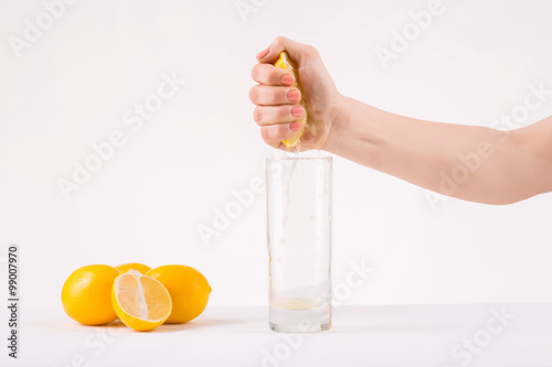 Female hand squeezing piece of orange to get juice.