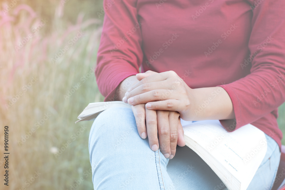 Girl laying on a book on his leg, Nature scene blurred. Warm rose.