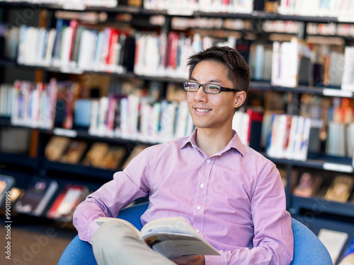 Happy male student holding books at the library © Sergey Nivens