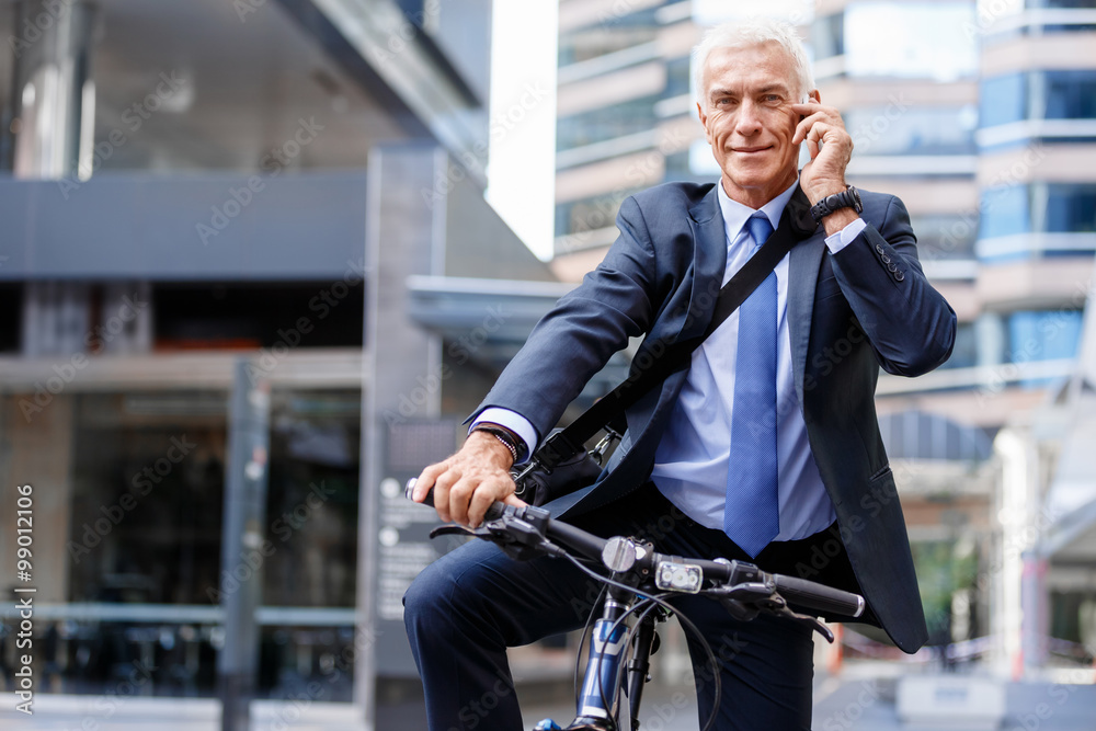 Successful businessman on bicycle with mobile phone Successful businessman on bicycle with mobile phone