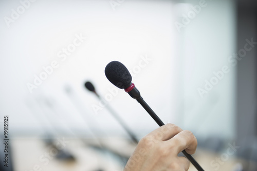 Close up of a hand holding a business conference microphone in a
