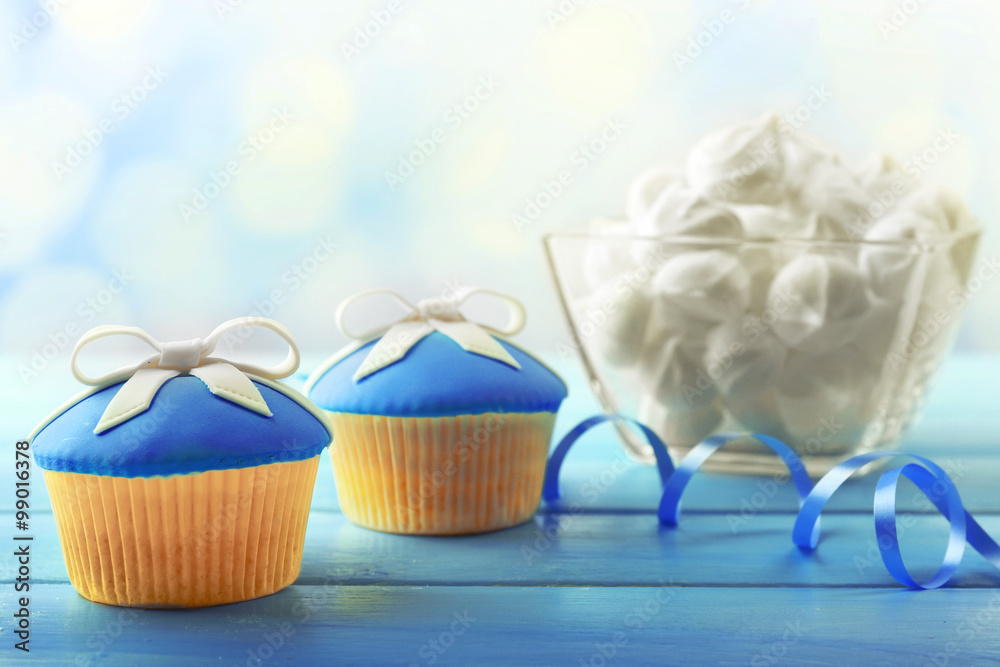 Tasty cupcake with bow on color wooden table, on bright background Tasty cupcake with bow on color wooden table, on bright background