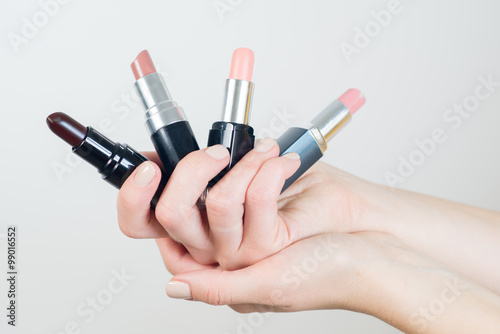 hand holding a few lipsticks on white background
