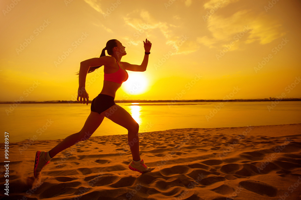 Woman jogging on the beach at sunset 