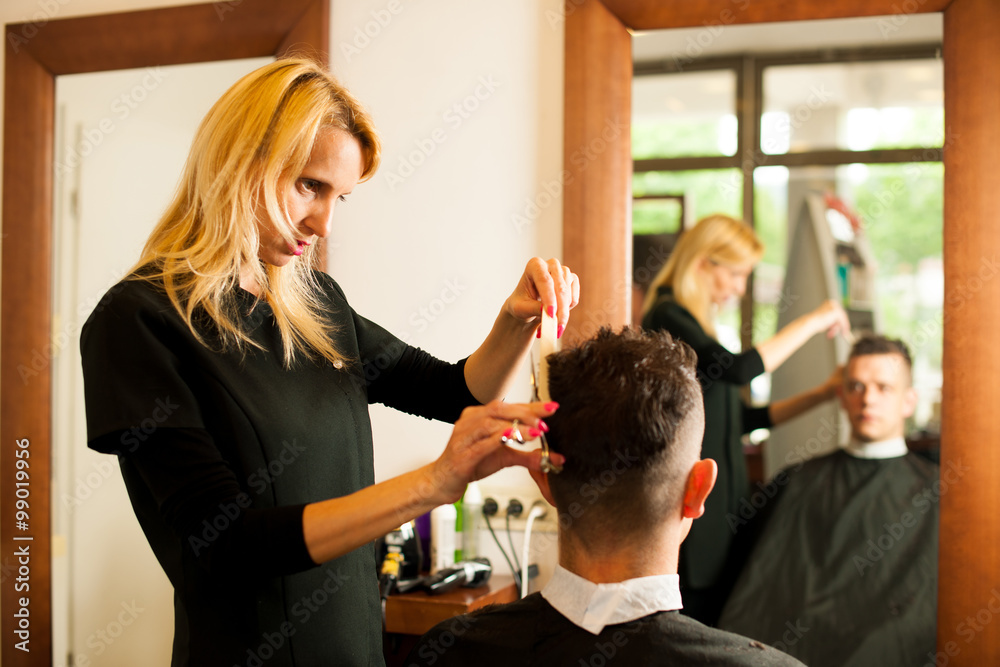 Female hairdresser cutting hair of smiling man client at beauty Female hairdresser cutting hair of smiling man client at beauty