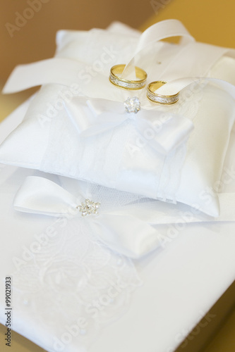 Обручальные кольца из белого и желтого золота на подушечке для колец