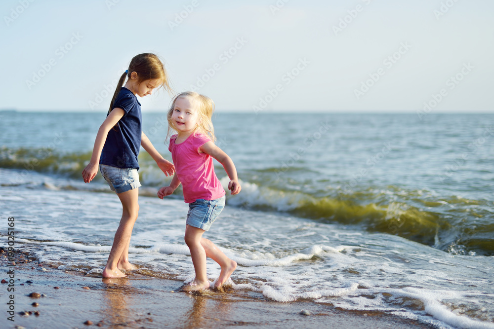 Two little sisters having fun on a sandy beach Two little sisters having fun on a sandy beach