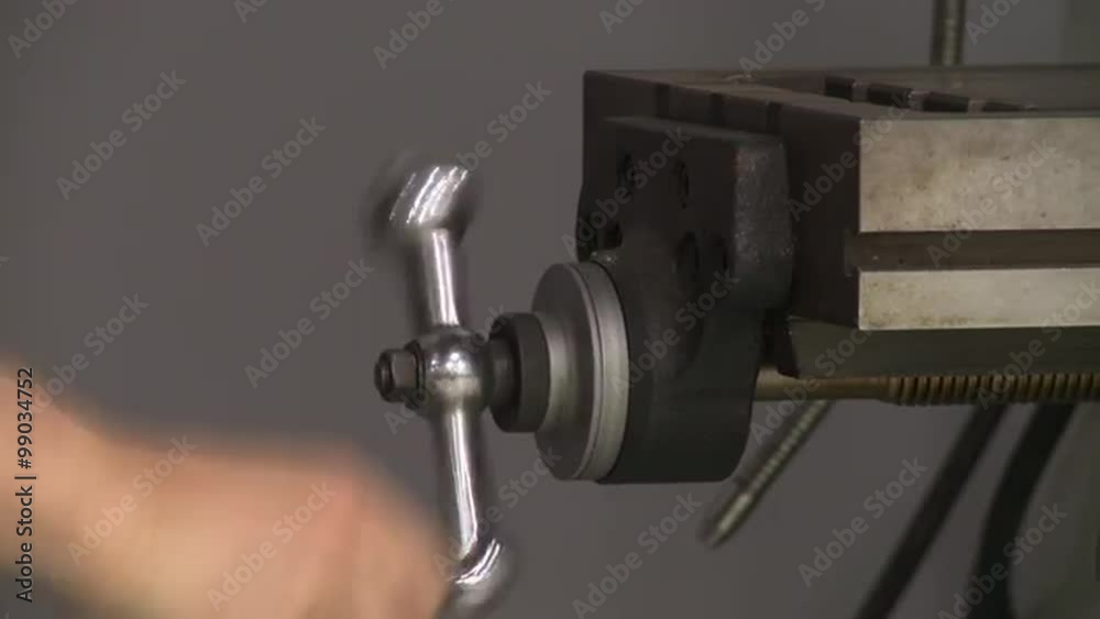 Close up of worker's hand turning a handle on a milling machine. Close up of worker's hand turning a handle on a milling machine.