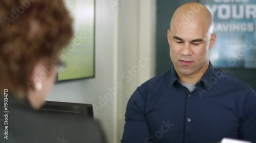 Friendly bank cashier conducts business with a customer.  Camera mounted on jib arm.