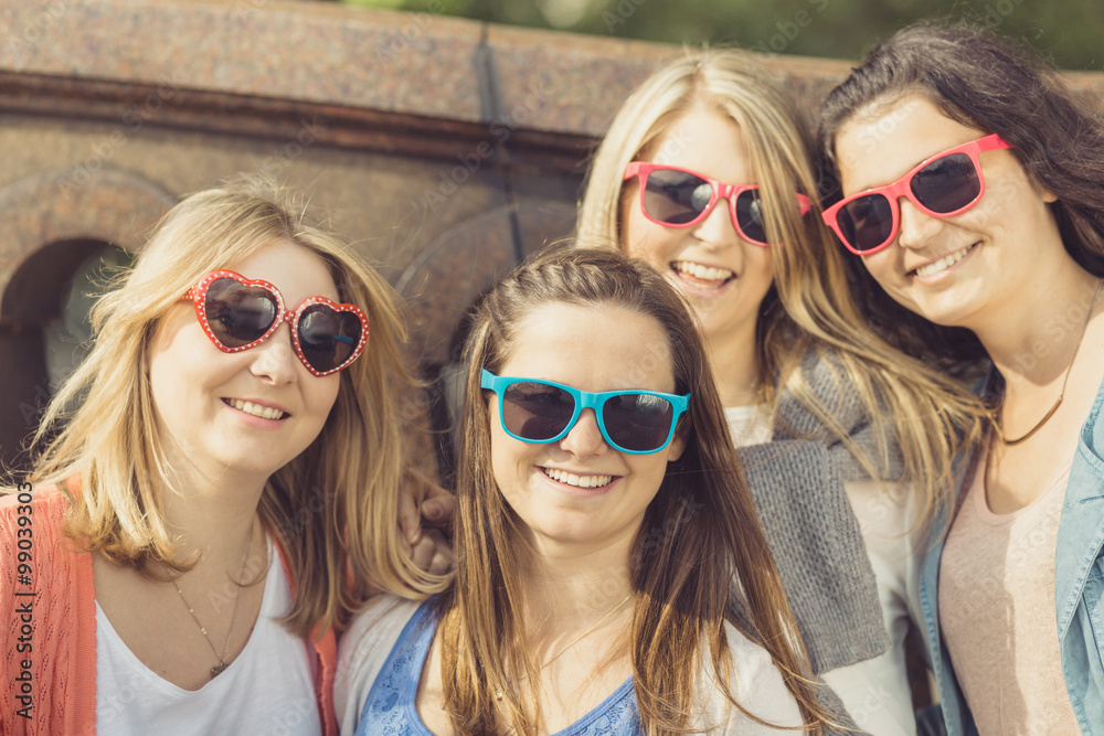 Vier junge Frauen mit Sonnenbrille posieren